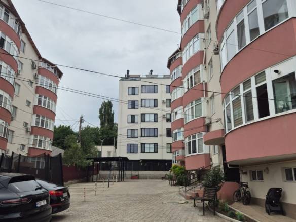 Двор между современными жилыми домами с красно-белыми фасадами — городской пейзаж, где жизнь теперь измеряется этажами
